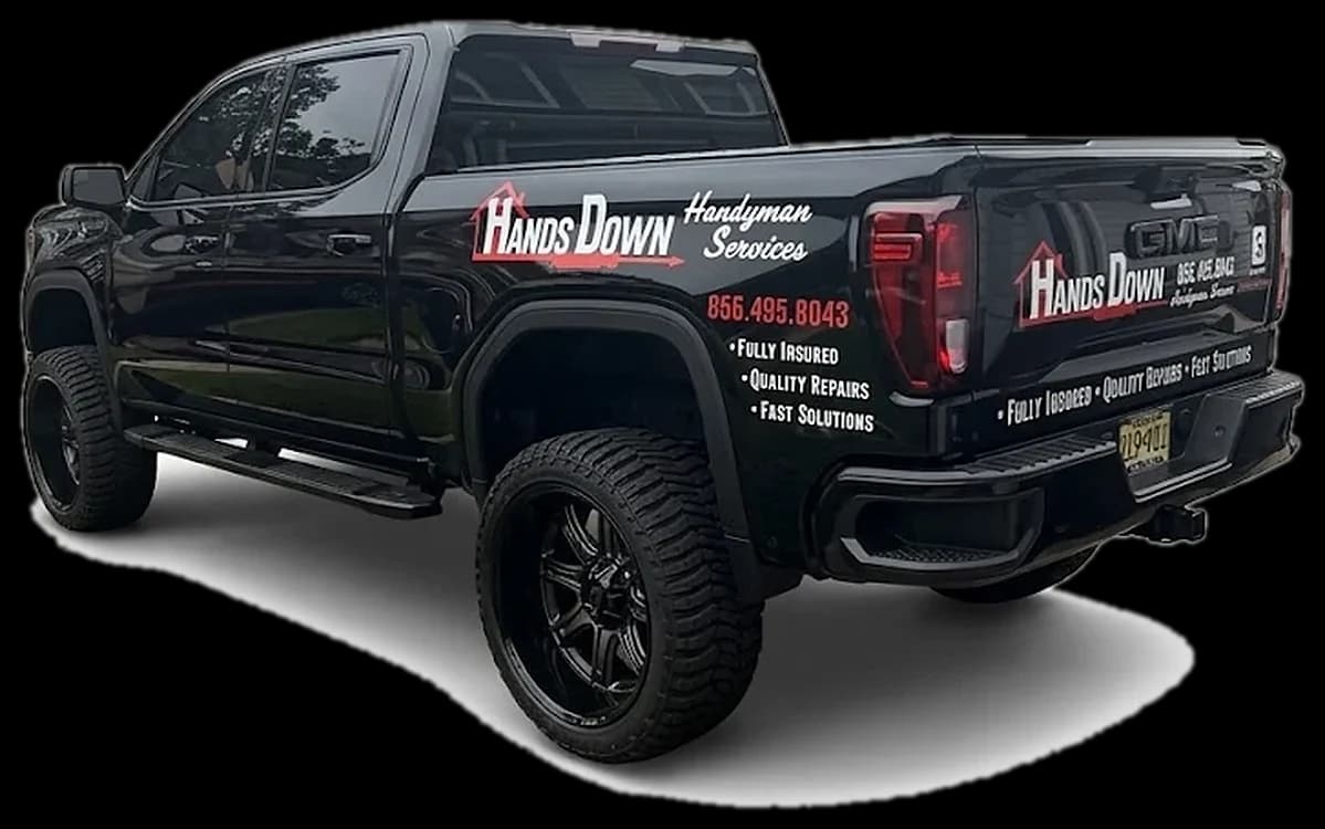 Hands Down Handyman's black GMC pickup, lettered with the logo and (856) 495-8043